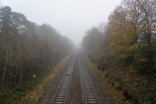 Fog shrouds the British countryside, and railway lines stretch off into the distance.
