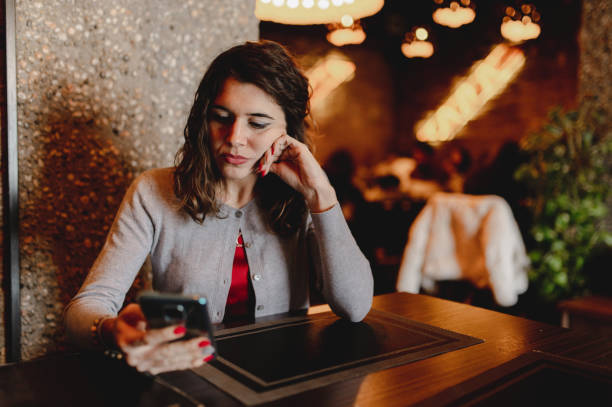 istock Young attractive woman sitting in table restaurant with copy space. lady using smartphone with cheerful face. 1290467887