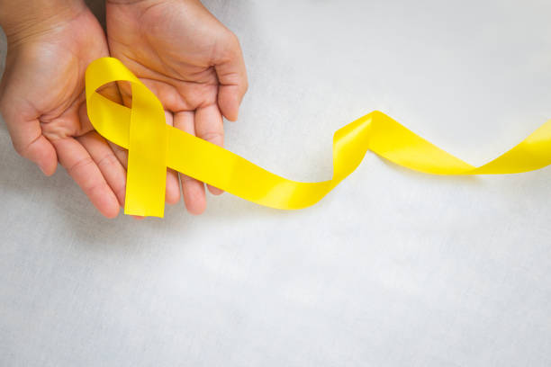 Hand holding Yellow ribbon on white background, copy space. Bone cancer, Sarcoma Awareness, childhood cancer, cholangiocarcinoma, gallbladder cancer, world Suicide Prevention Day. Health concept.
