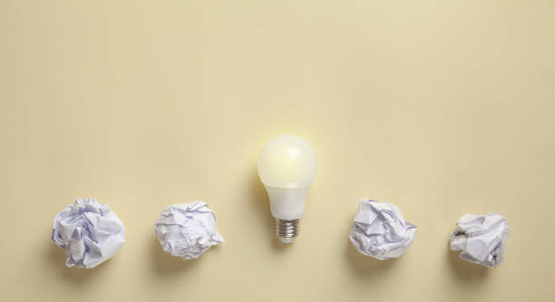 istock Light bulb and crumpled papers on the yellow background. 1290470951