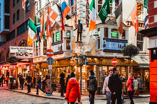 Dublin, Ireland - November 8, 2018: Famous Oliver St. John Gogarty's Hostel and pub with international flags in autumn. Temple Bar. View of Irish popular place with live music. Walking people on road