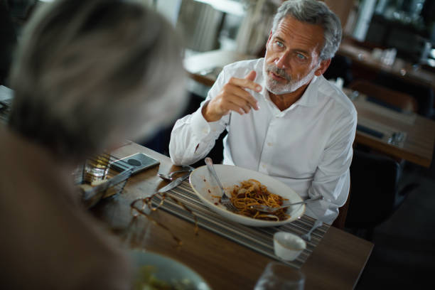 business colleagues eating lunch during lunch break at the restaurant. - eating senior adult color image spaghetti imagens e fotografias de stock