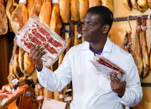 Photo of Salesman checking quality of ham