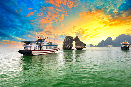 Dreamy sunset in Halong bay, Vietnam. Tourist cruise ship floating among limestone rocks. This is the UNESCO World Heritage Site, it is a beautiful natural wonder in northern Vietnam