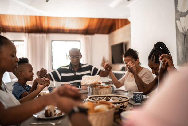 Family saying grace over food at home Family saying grace over food at home saying grace stock pictures, royalty-free photos & images