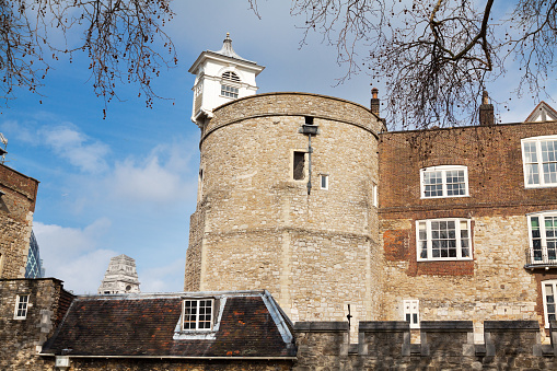 Detail of complex of Tower of London. In foreground is roof of lower building. At tower in background is small spire