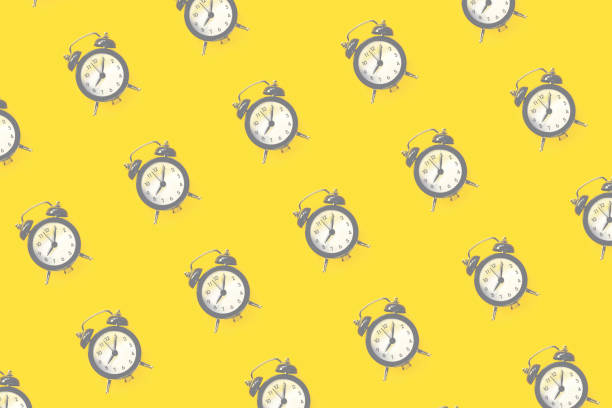 istock Pattern made of alarm clock on yellow background, top view 1290476223
