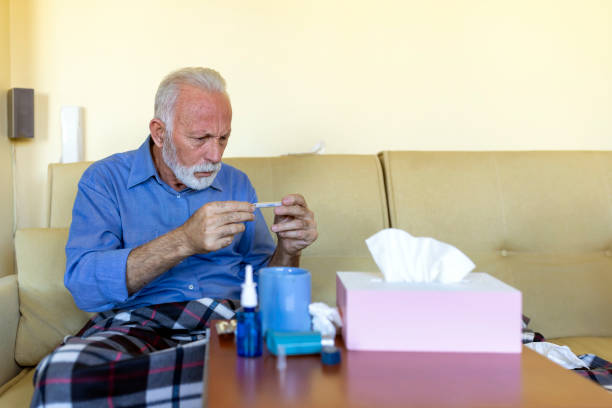 istock Sick Older Man is Feeling Sick and Checking his Temperature. 1290482714