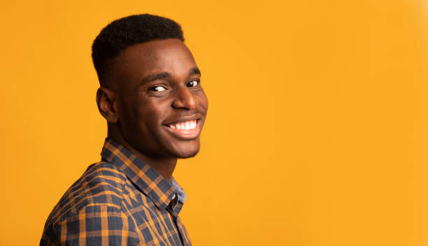 istock Young African American Guy Smiling To Camera, Standing Half-Turned Over Yellow Background 1290488221