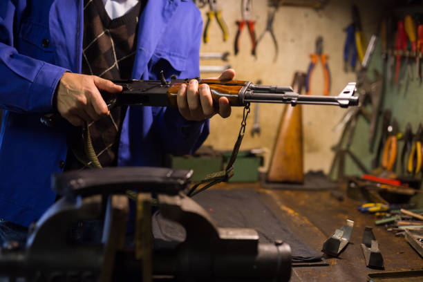 istock Gunsmith with Kalashnikov assault rifle in weapons workshop 1290488409