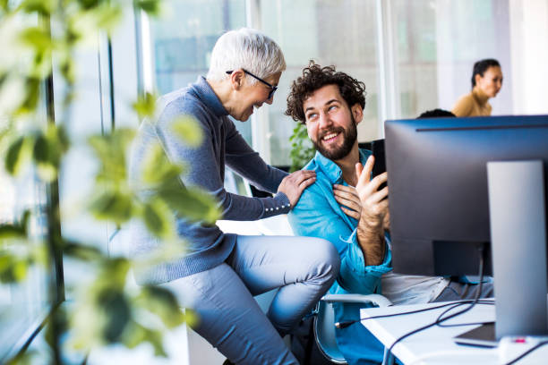 dos colegas, sonriendo y hablando durante la pausa para el café en el cargo. - break office 30s 20s fotografías e imágenes de stock