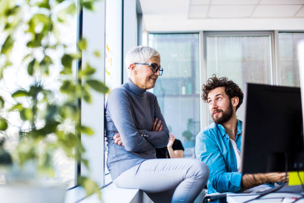 istock Two colleagues talking, thinking, smiling in their office. 1290492285