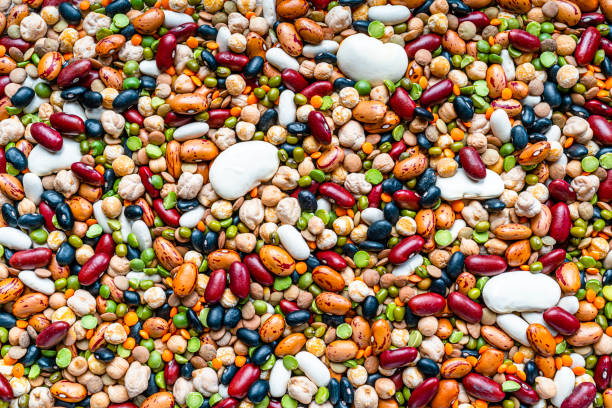 Mixed dried legumes background Food Backgrounds: overhead view of a large variety of dried mixed beans and legumes. The composition includes green, yellow and brown lentils, chick-peas, black beans, Pinto beans, Kidney beans, fava beans, white beans, mung beans, soy beans among others. High resolution 42Mp studio digital capture taken with SONY A7rII and Zeiss Batis 40mm F2.0 CF lens bean stock pictures, royalty-free photos & images