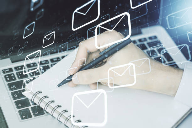 istock Creative abstract postal envelopes hologram with hand writing in diary on background with laptop, email and notification concept. Multiexposure 1290493596