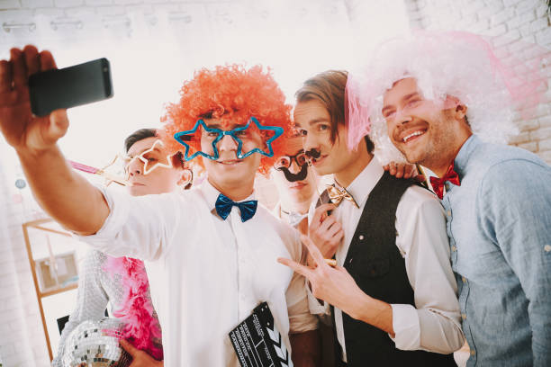 Gay guys taking selfie on phone at party. Gay guys in bow ties taking selfie on phone at party. gay man men sunglasses party stock pictures, royalty-free photos & images