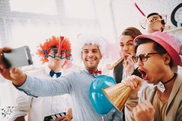 Gay guys taking selfie on phone at party. Gay guys in bow ties taking selfie on phone at party. gay man men sunglasses party stock pictures, royalty-free photos & images