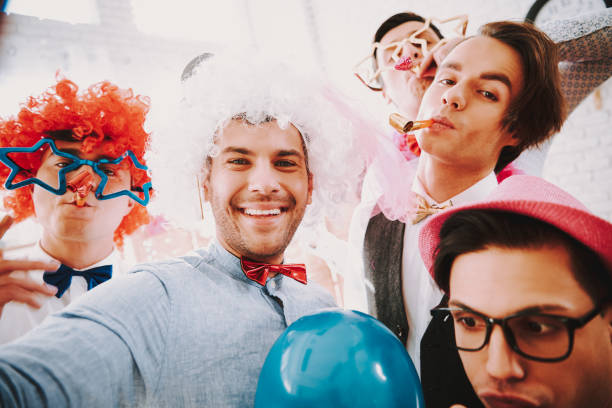 Gay guys taking selfie on phone at party. Gay guys in bow ties taking selfie on phone at party. gay man men sunglasses party stock pictures, royalty-free photos & images