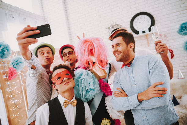 Gay men taking selfie on phone at party. Gay men in bow ties taking selfie on phone at party. gay man men sunglasses party stock pictures, royalty-free photos & images