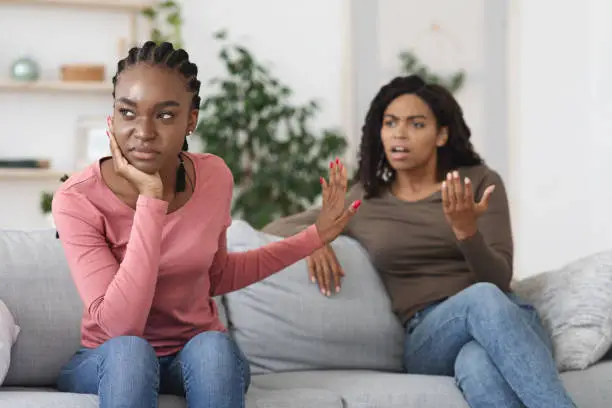 Photo of Annoyed black woman showing stop gesture to her scolding girlfriend