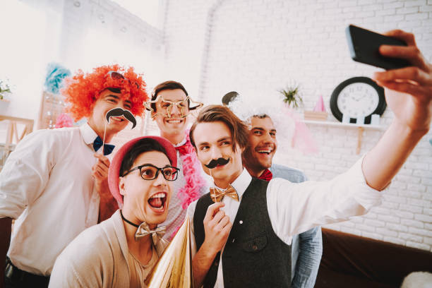 Gay guys taking selfie on phone at party. Gay guys in bow ties taking selfie on phone at party. gay man men sunglasses party stock pictures, royalty-free photos & images