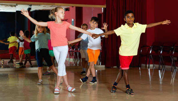 istock Smiling children primary school trying dancing salsa dance in mo 1290495105