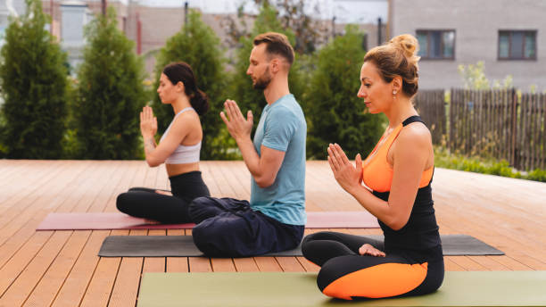 istock Group of slim people while meditation in park on mats 1290495381