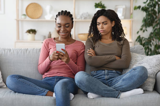 istock Annoyed black woman looking at girlfriend smartphone screen 1290495519