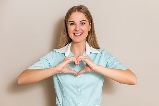 Portrait of beautiful nurse showing heart shape with hands