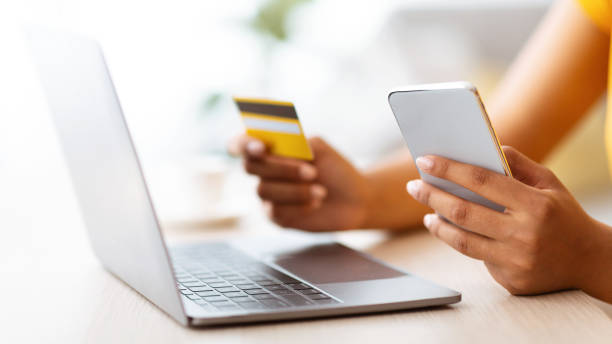 istock Black lady using smartphone and credit card sitting at desk 1290498620