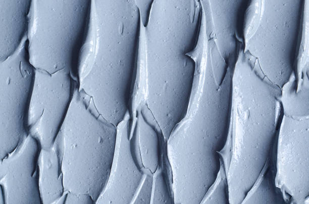 istock Gray bentonite facial clay (mask, face cream, body wrap) texture close up, selective focus. Abstract background with brush strokes. 1290499584