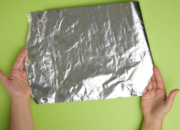 istock female hands holds crumpled silver foil on a green background 1290500088