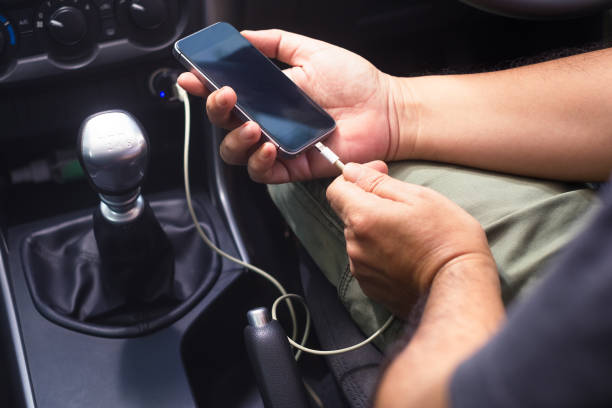 Charging Phone in Car Closeup hands holding smartphone and going to charge battery by power supply socket in private car mobile phone charger stock pictures, royalty-free photos & images