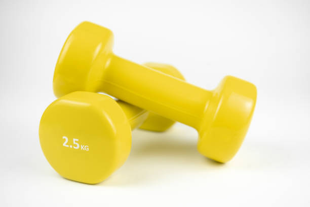 zwei gelbe 2,5 kg hanteln auf weißem hintergrund - gym yellow muscular build dumbbell stock-fotos und bilder