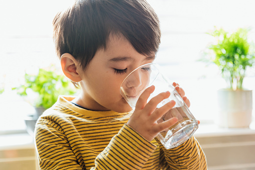 Close up of a young boy drinking from a glass of water in the Northeast of England.