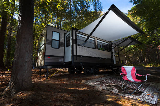 istock Inviting red  chair in front of a camper trailer during autumn 1290513548