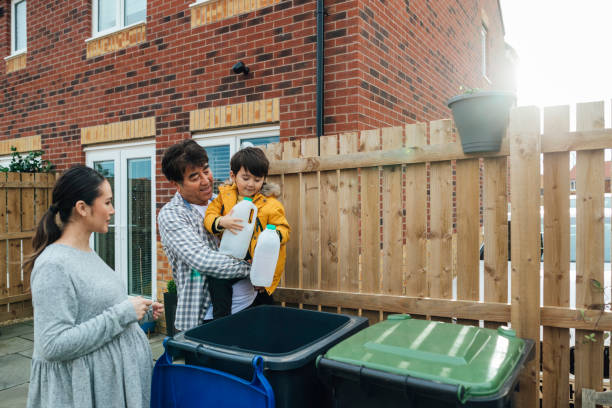 Helping Out with the Recycling Three generation family of a father daughter and grandson standing outside disposing of household recycling into an outdoor bin. The young boy is helping while learning about recycling. central asian ethnicity photos stock pictures, royalty-free photos & images