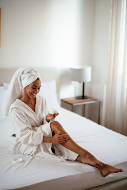 istock Young woman applying body lotion on legs 1290517708