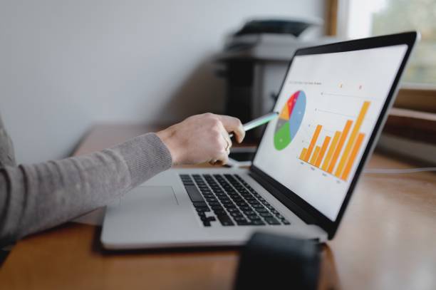istock unrecognizable woman hand pointing with pen computer desktop showing graphs. 1290517788