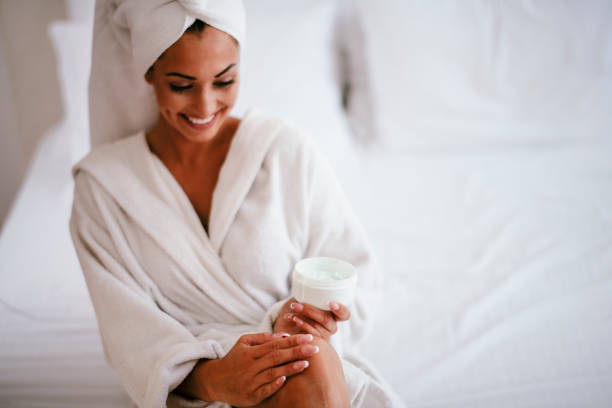 istock Young woman applying body lotion on legs 1290518266