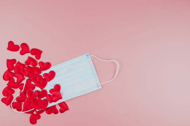 istock Red hearts and medical face mask on a pink background. Flat lay, copy space 1290523536