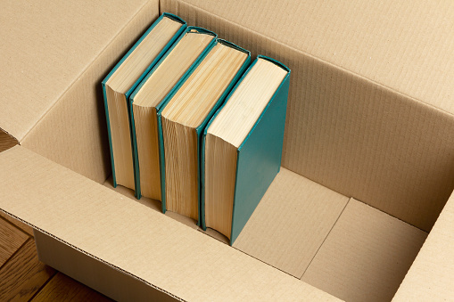 Several books in a cardboard box on the floor of the room