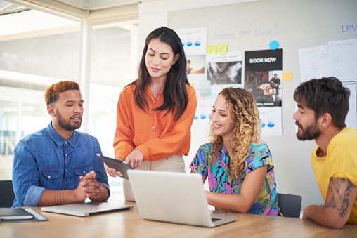 Shot of a group of young businesspeople using a laptop and digital tablet in a modern office