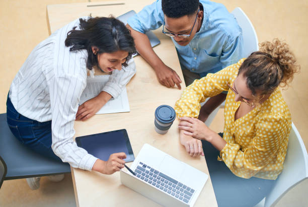 Collaboration across departments keeps an organization running smoothly Shot of a group of young businesspeople using a laptop in a modern office project management photos stock pictures, royalty-free photos & images