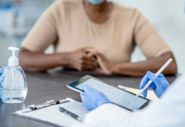 istock Nurse using modern technology tablet with African American patient 1290532325
