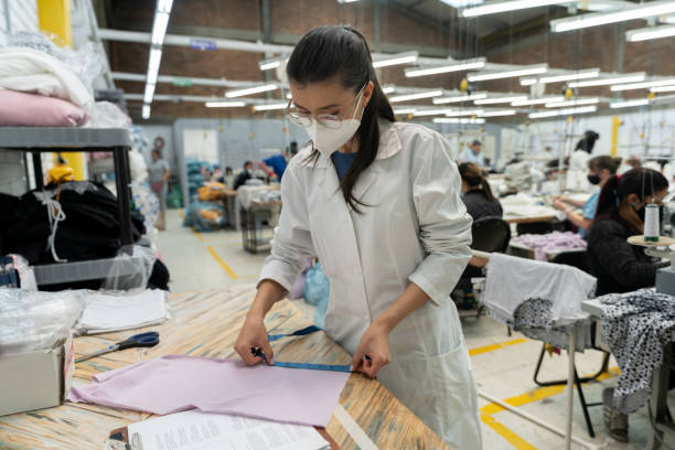 istock Supervisor measuring fabrics at a clothing factory while wearing a facemask 1290533826