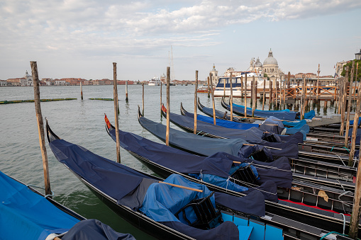 Venice, Italy - July 1, 2018: Panoramic view of Laguna Veneta coast of Venice city with gondolas. Landscape of summer morning day and dramatic blue sky