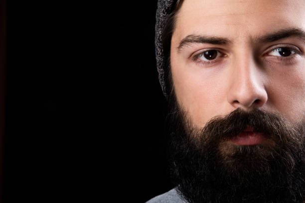 Studio shot of a handsome young man looking thoughtful against a siyah background