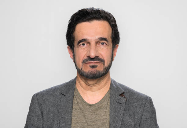 Portrait of senior man standing against grey background.