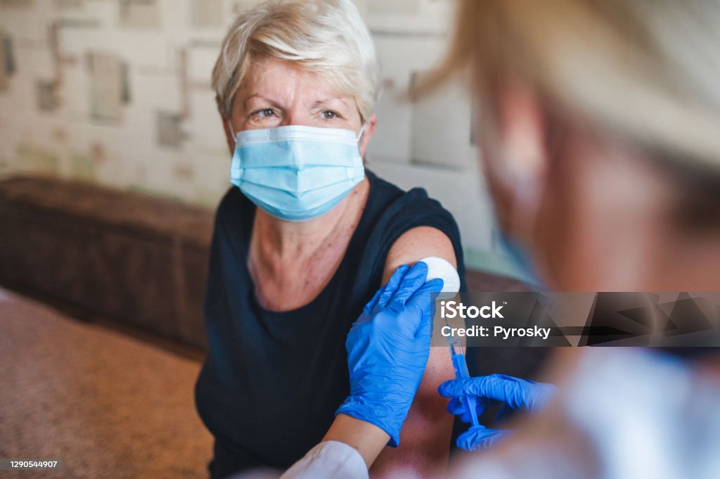 Patient getting vaccination at home Senior woman getting a vaccine from her doctor in her home during a house visit during the COVID-19 pandemic.
Concept photo. Vaccination Stock Photo