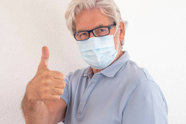 istock Coronavirus. Attractive senior man wearing protective face mask due to coronavirus looking at camera. Optimist and positive elderly with thumb up 1290545259